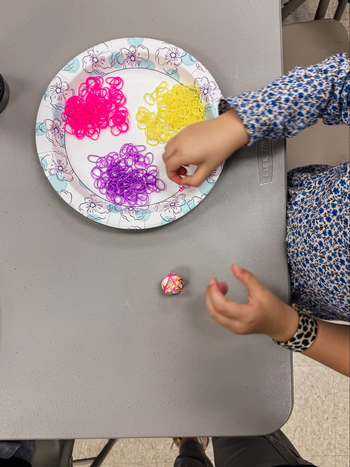 A child making a bouncy ball with colorful rubber bands