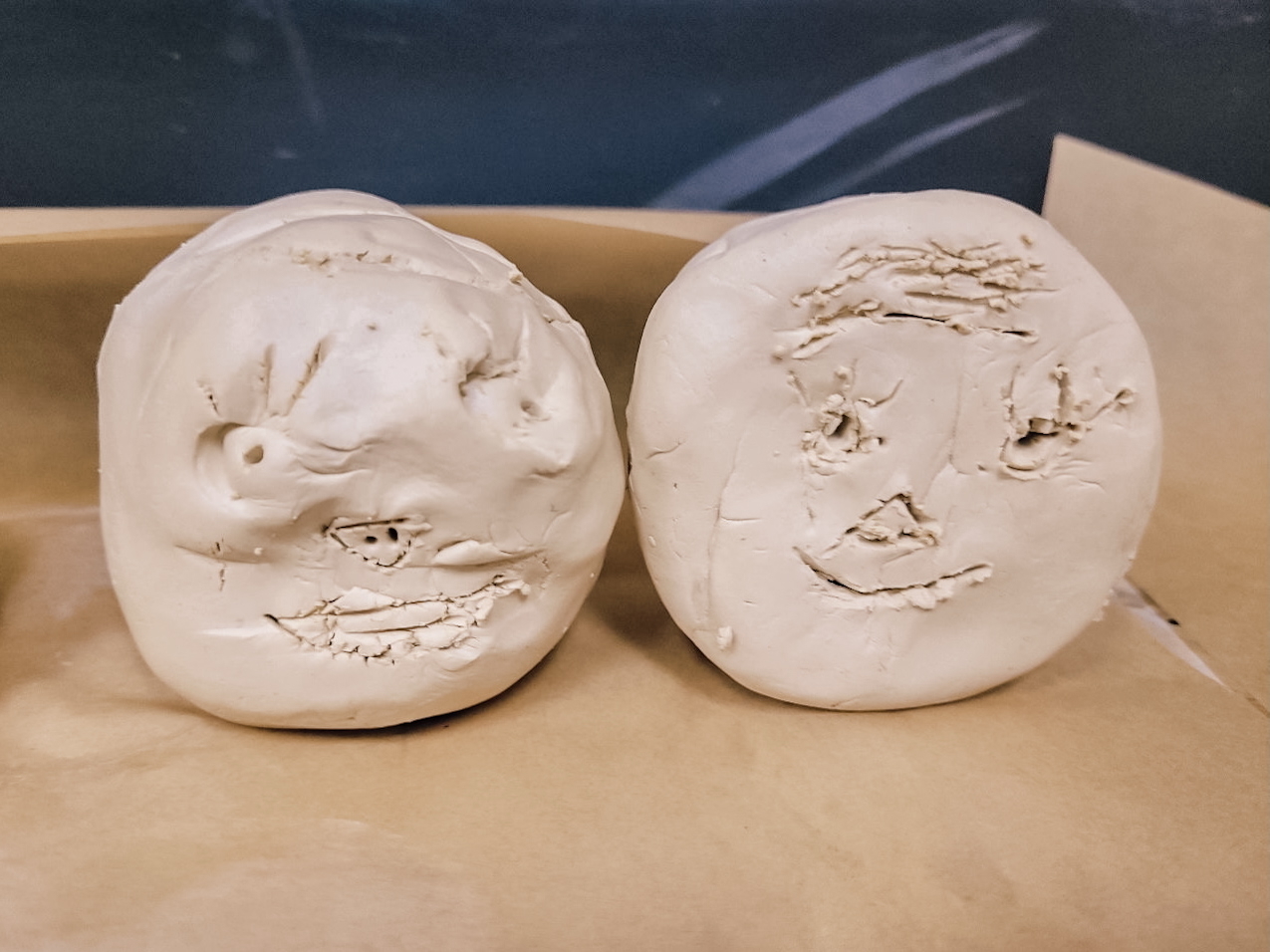 Two clay heads with faces carved by children