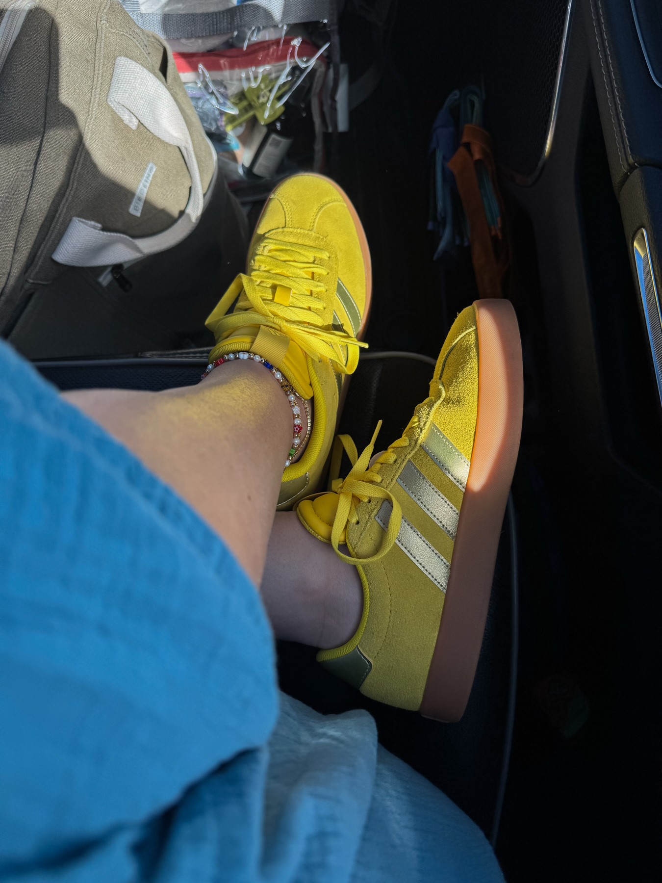 Auto-generated description: A person wearing yellow Adidas sneakers with gum soles rests their feet inside a car.