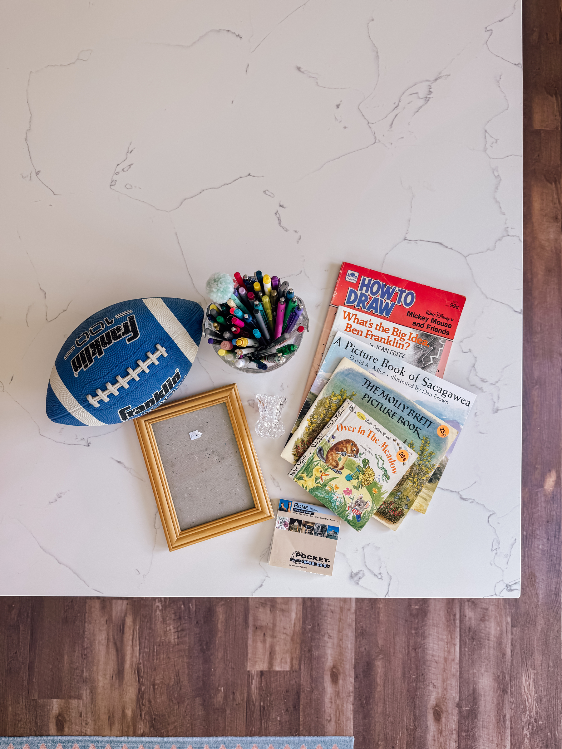 A counter displays a football, a frame, a jar of colored markers and pens, various books, and a folded map.