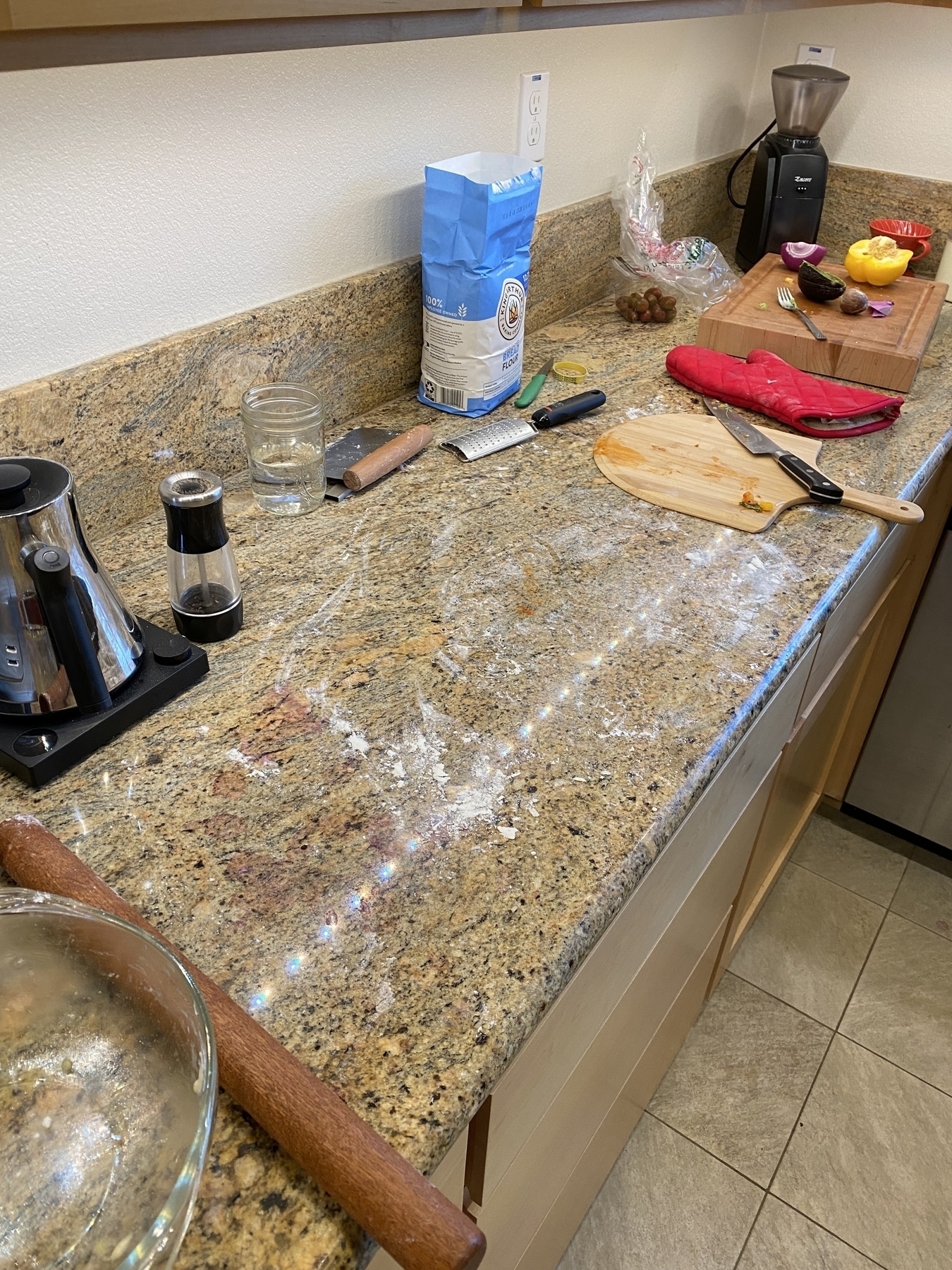 A messy kitchen countertop covered with the detritus from pizza crust making 